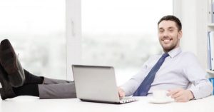 Blije man achter computer met benen op tafel werkt met Scan & Herken software