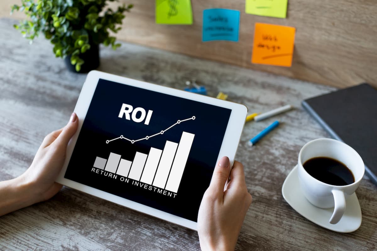 Bureau met kop koffie en tablet waarop ROI (return on investment) staat vermeld.