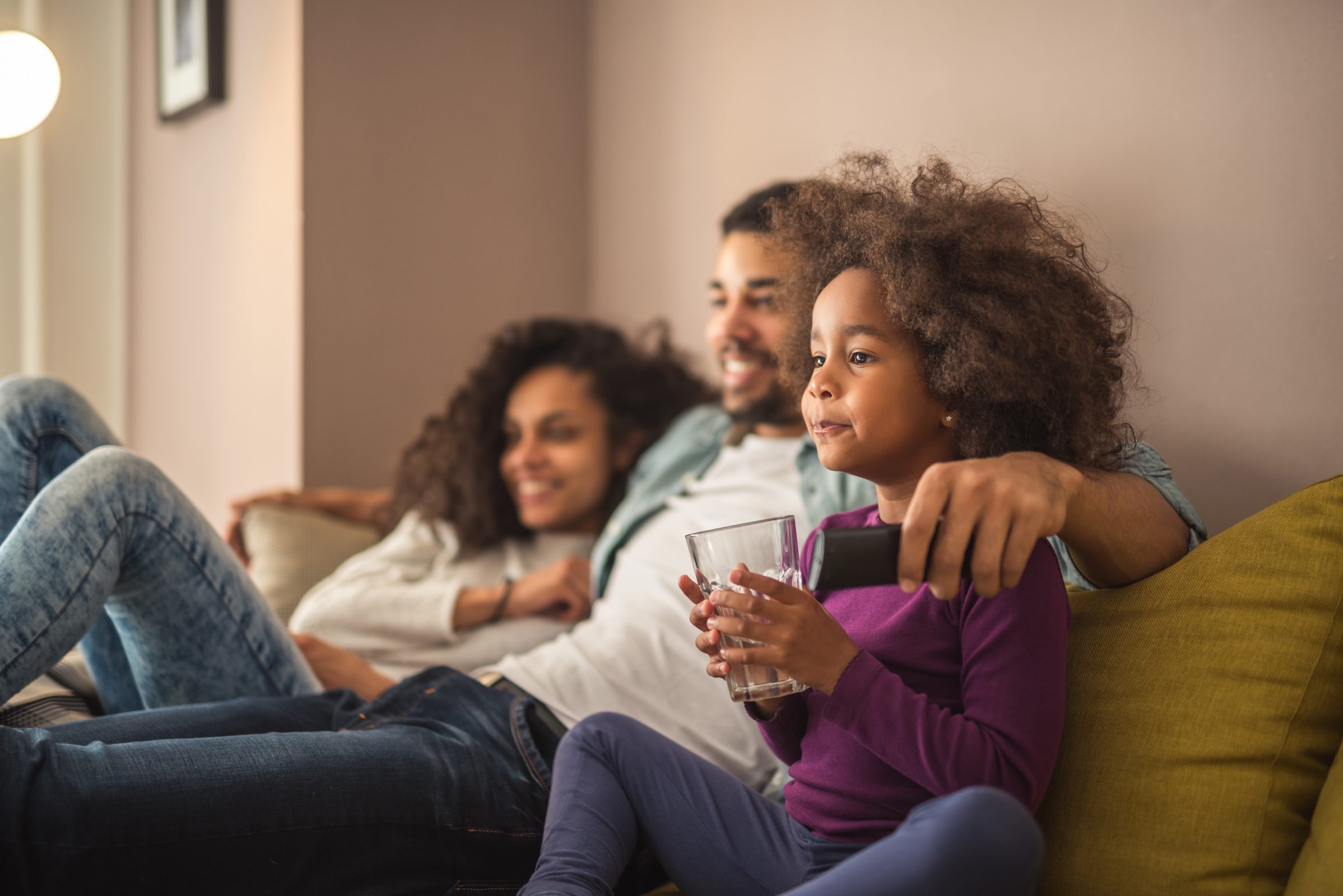 Man, woman and Child watching TV together on the couch