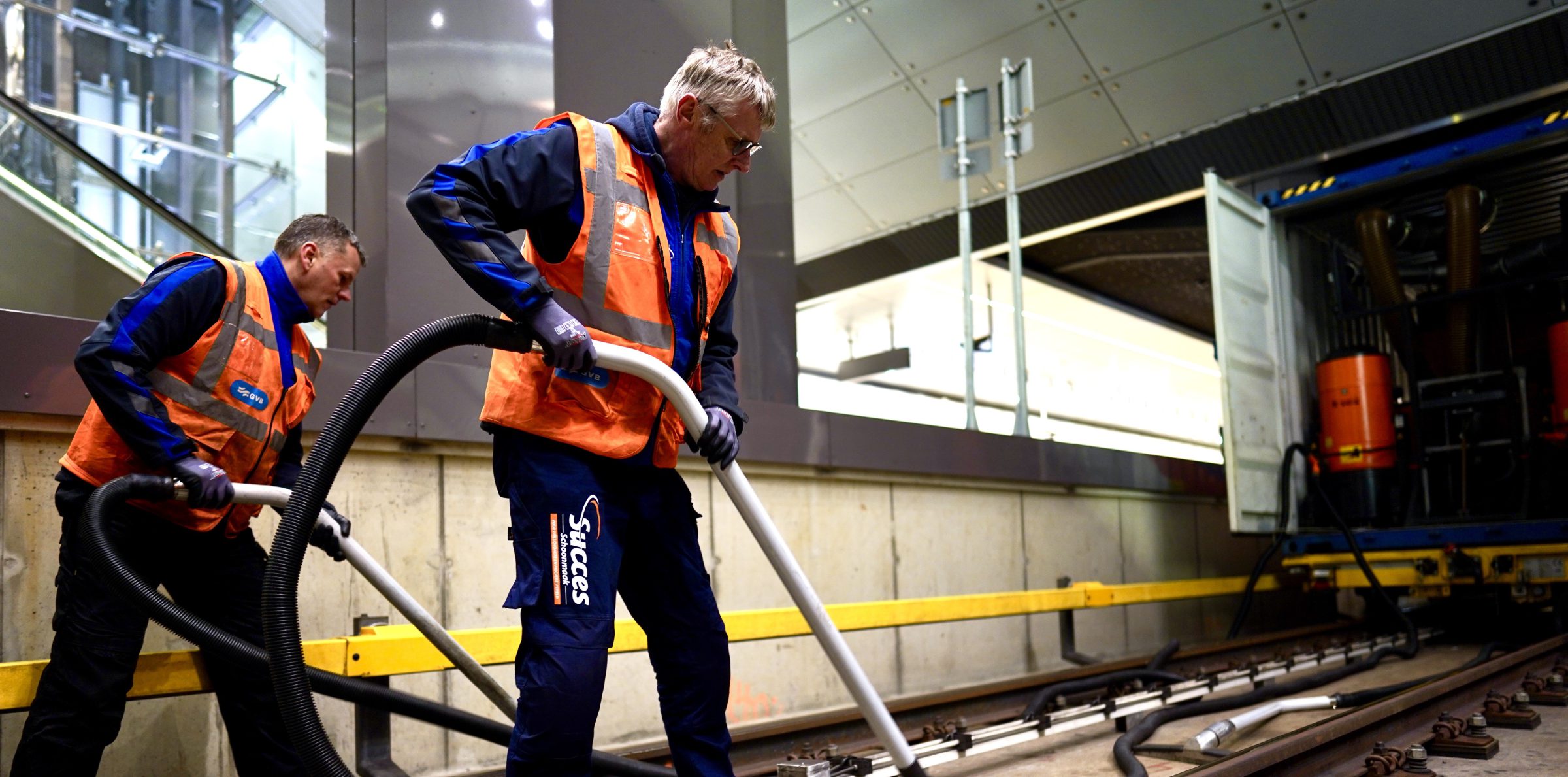 Two employees of Success Cleaning in orange vests are at work